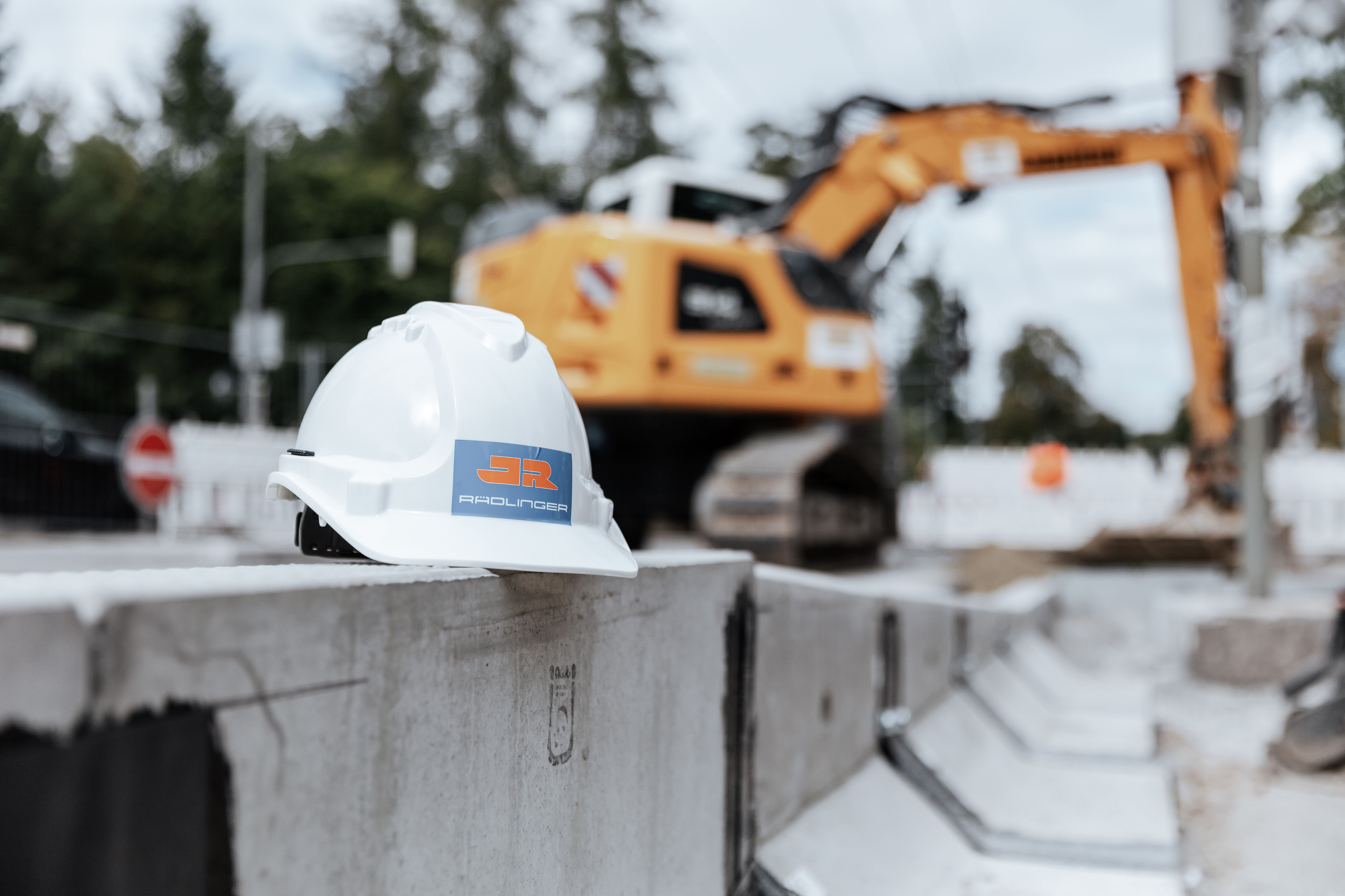 Rädlinger Bauhelm auf einer Baustelle, im Hintergrund Bagger