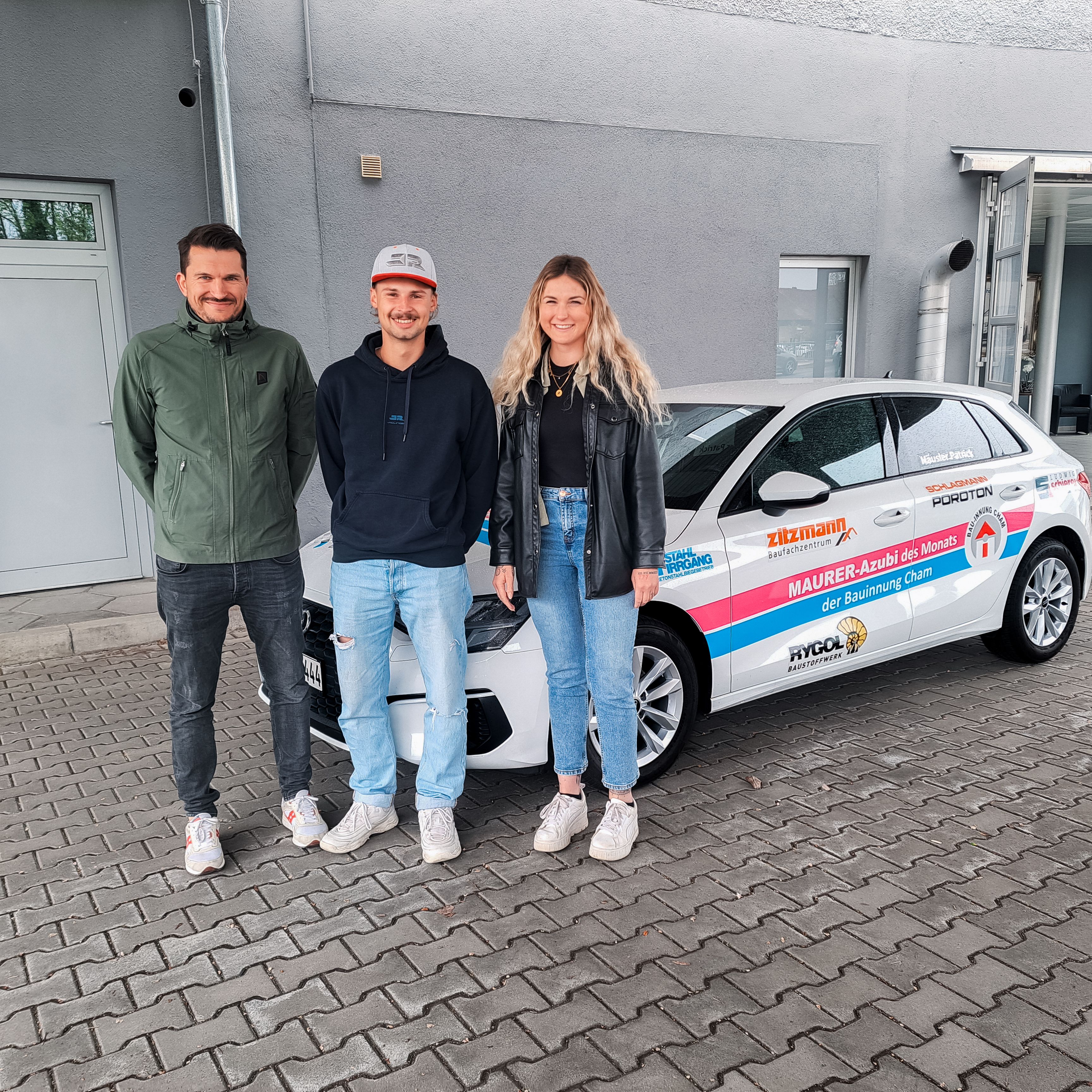 Maurer Azubi Patrick Häusler zusammen mit den beiden Ausbildungsbetreuern Nathalie Hirmer und Dominik Fischer bei der offiziellen Übergabe des Innungsautos.