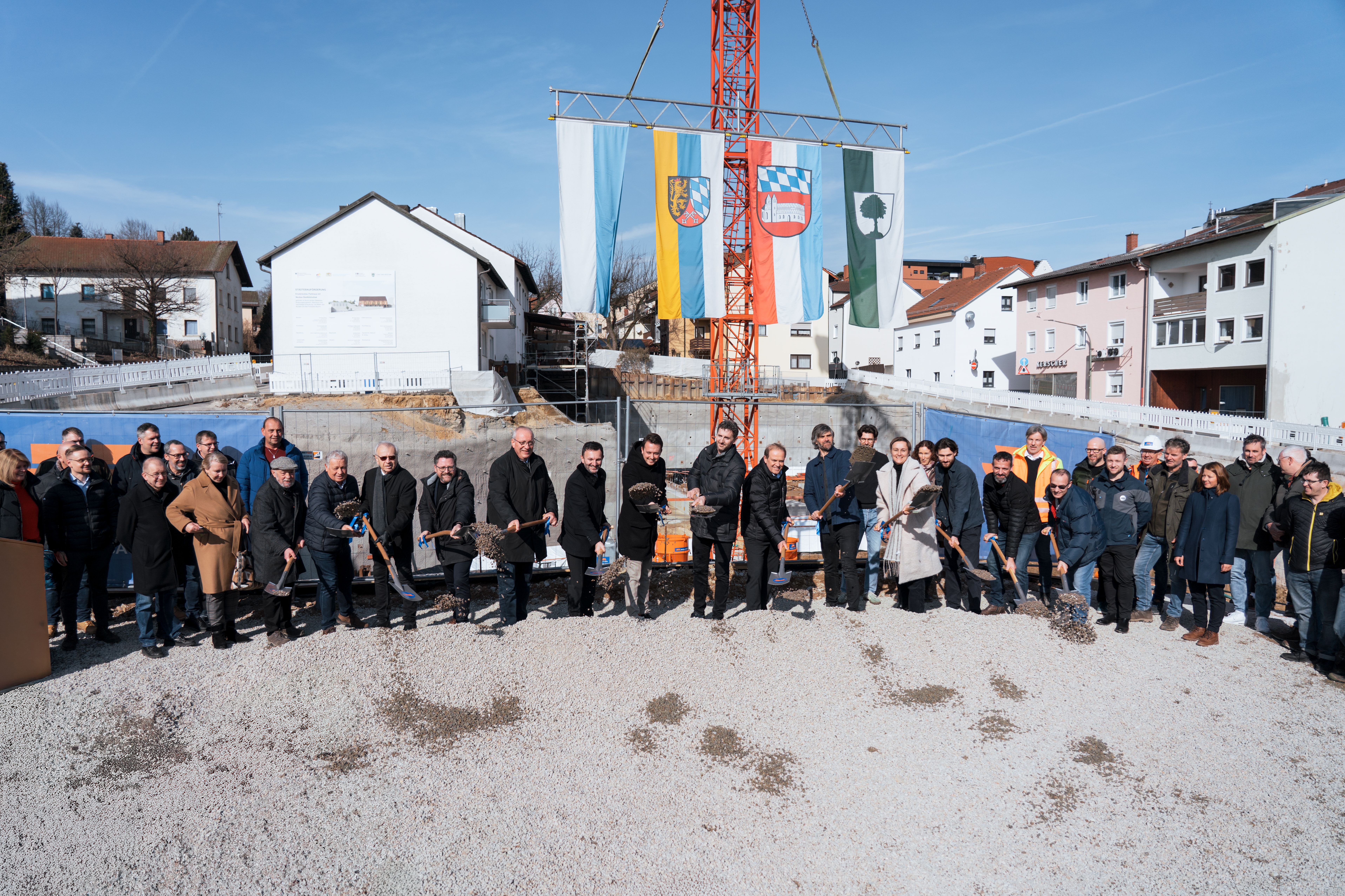 Die geladenen Gäste versammeln sich mit Schaufeln auf der Baustelle