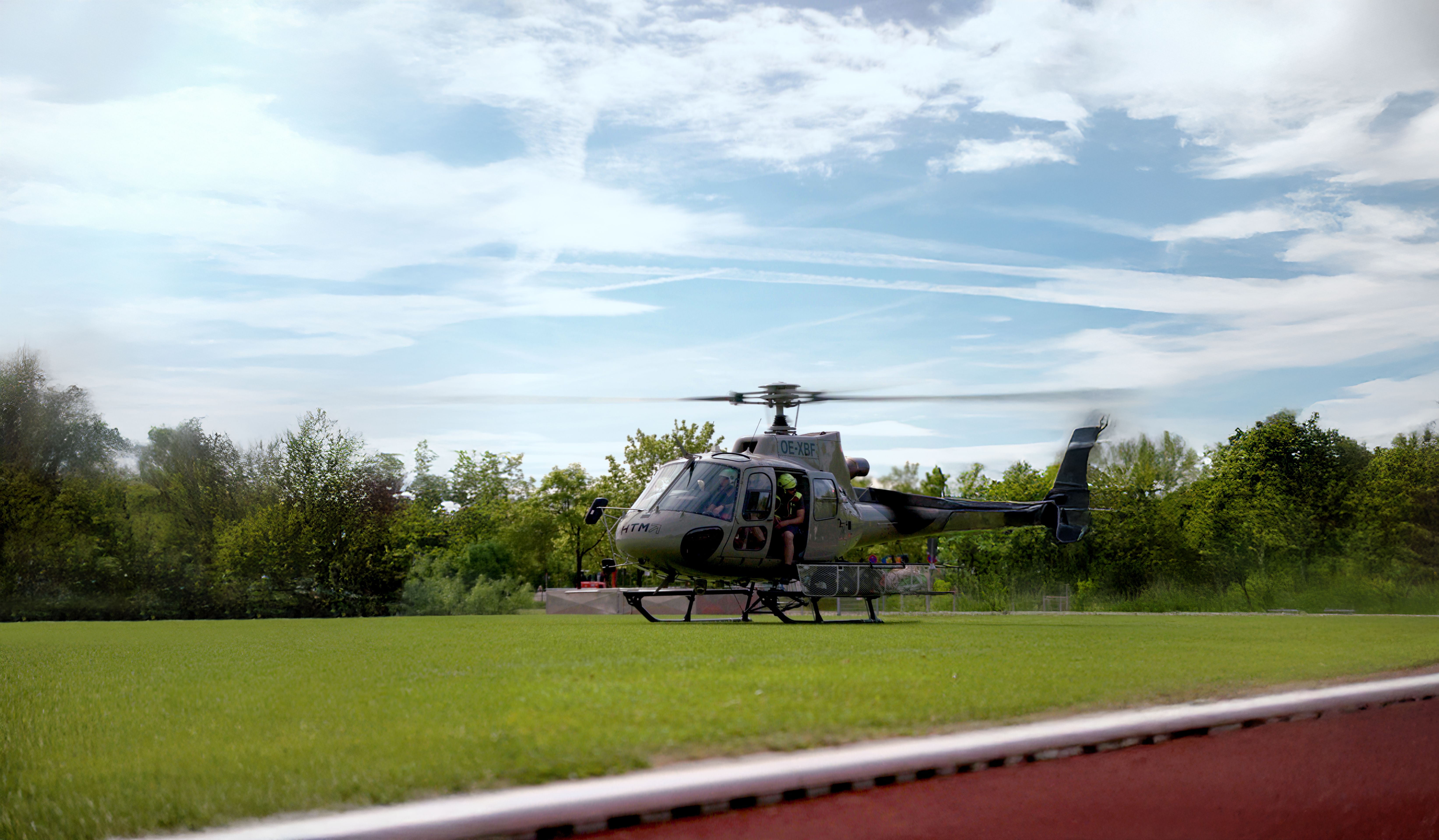 Helikopter auf der Grünfläche des Sportplatzes mit sich drehenden Rotorblättern