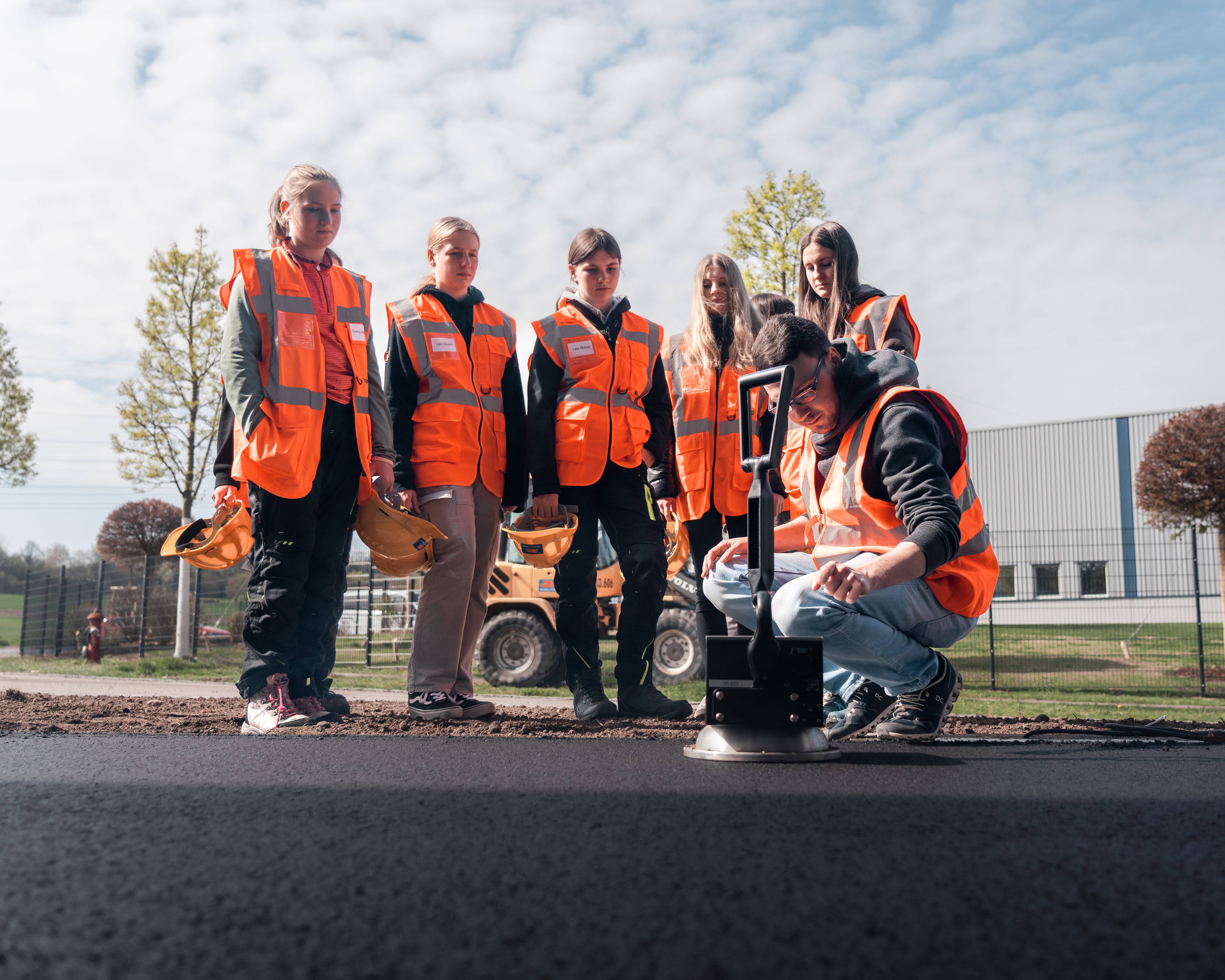 Girlsday 2023 bei Rädlinger: Mädels sehen bei der Prüfung des Asphalts einer frisch asphaltierten Straße zu