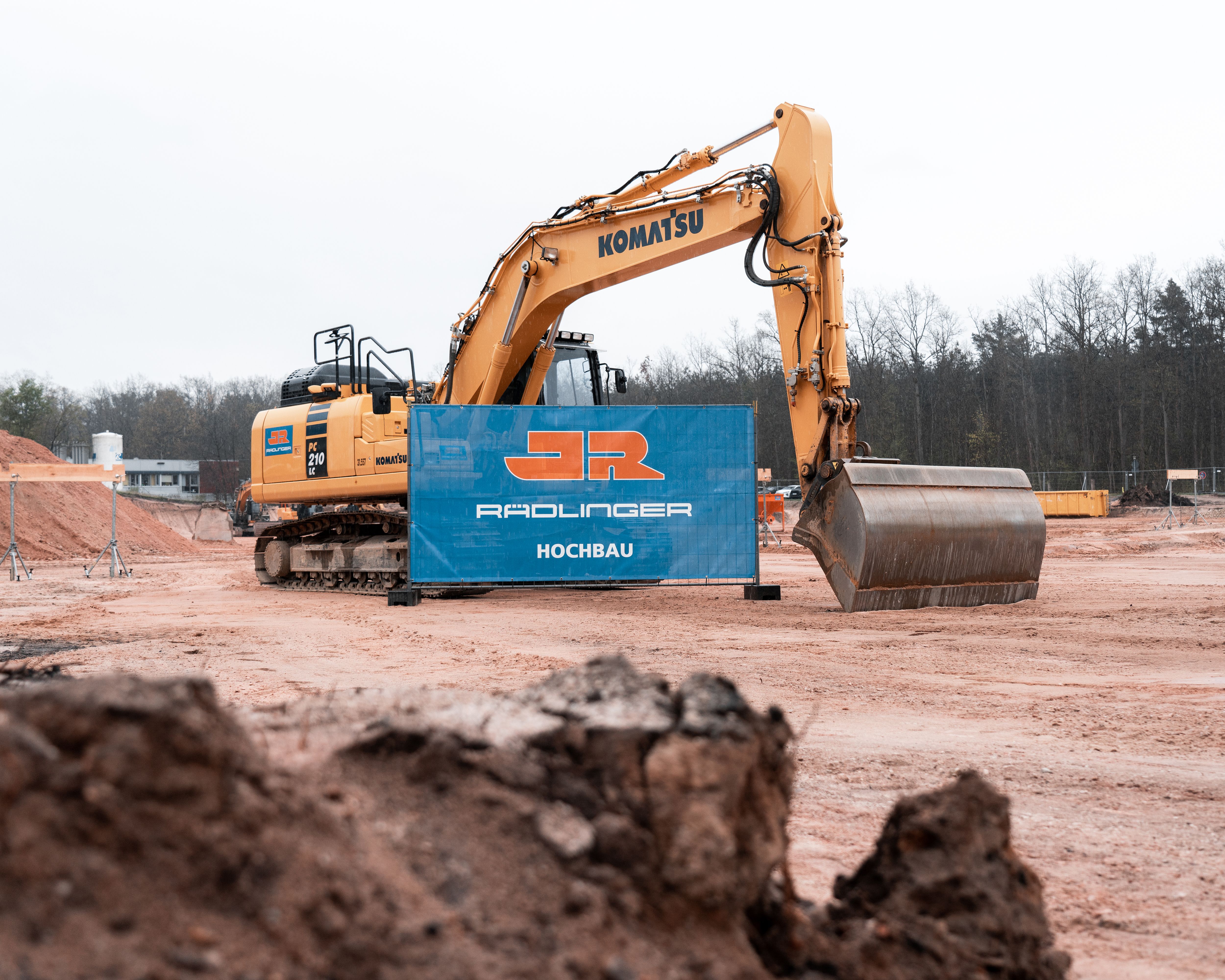 Grundsteinlegung Kinderklinikum Nürnberg: Baustellenbanner des JR Hochbaus und gelber Rädlinger Bagger von Komatsu