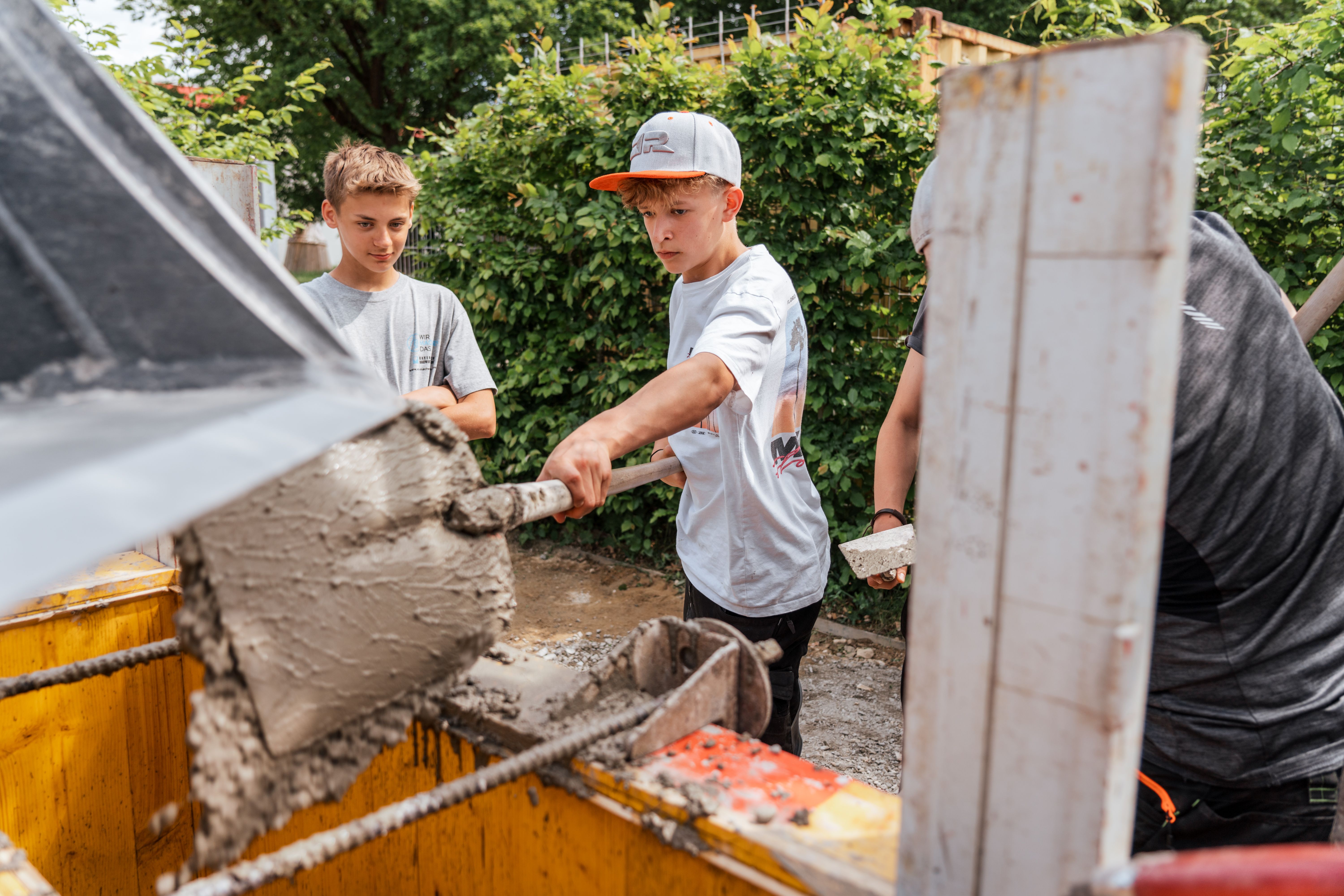 Ein Schüler kippt eine Ladung Beton in die Schalung für die Blocksteine.