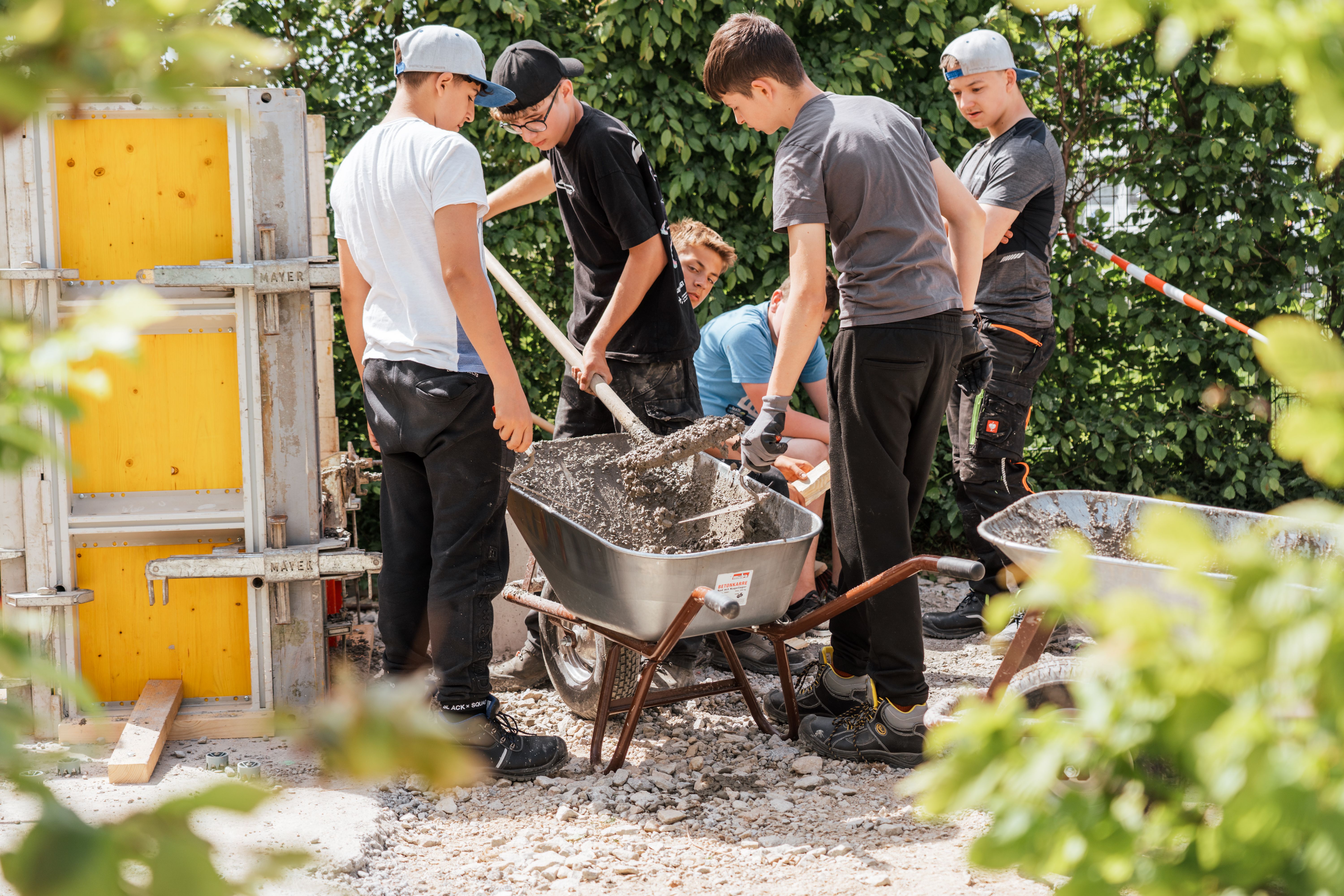 Die Schülerinnen und Schüler helfen zusammen, den frischen Beton weiterzuverarbeiten.