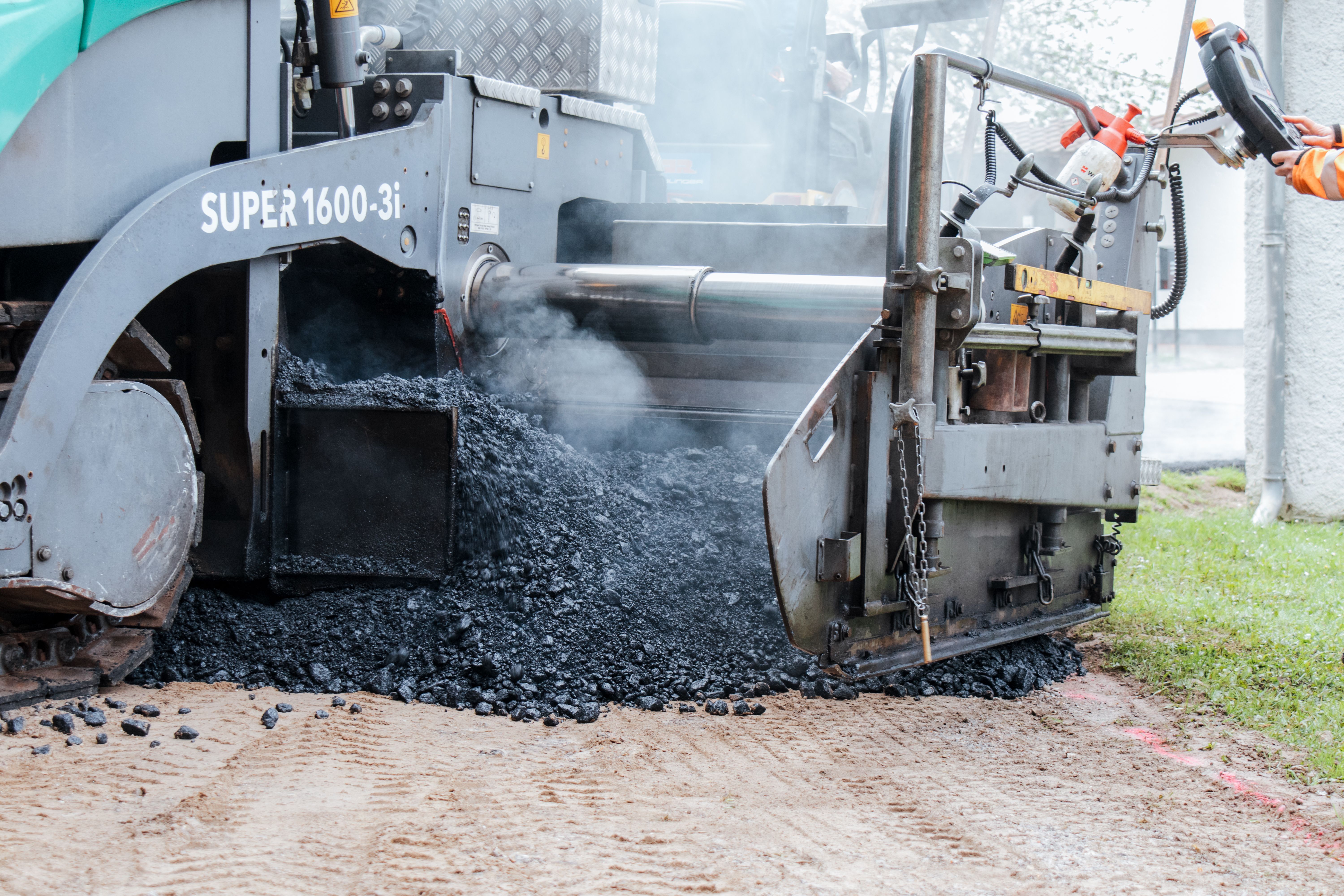 Temperaturabgesenkter Asphalt im Asphaltierer auf der Baustelle