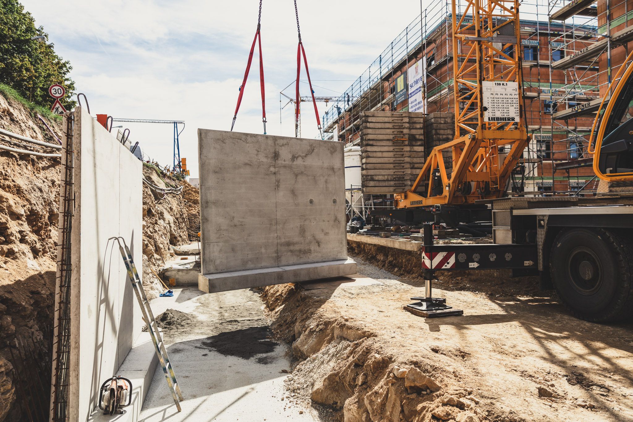 Kran hebt auf Baustelle ein Fertigteil aus Beton ein
