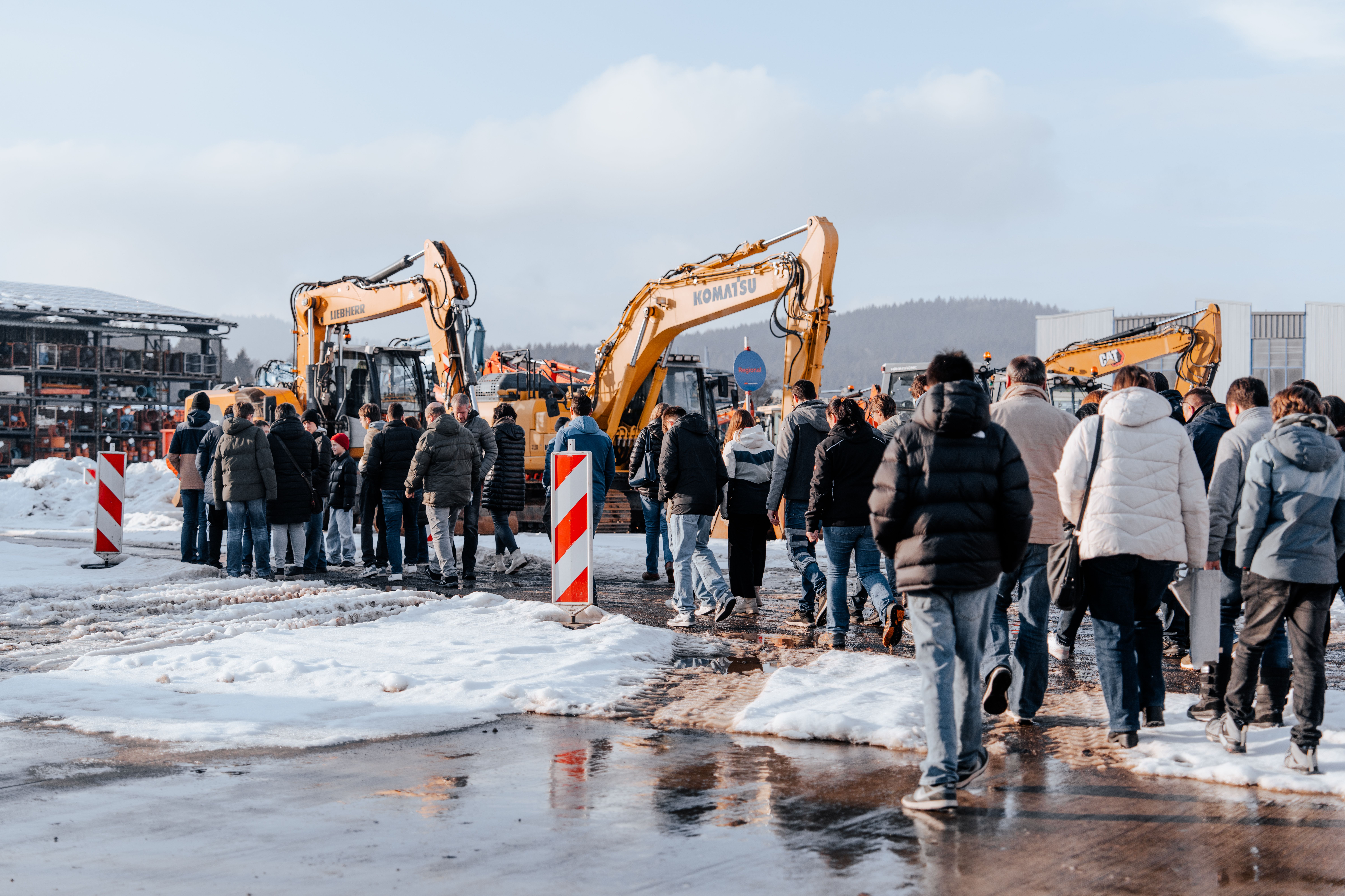 Die Besucher besichtigen die Baumaschinen auf dem Firmengelände in Weiding