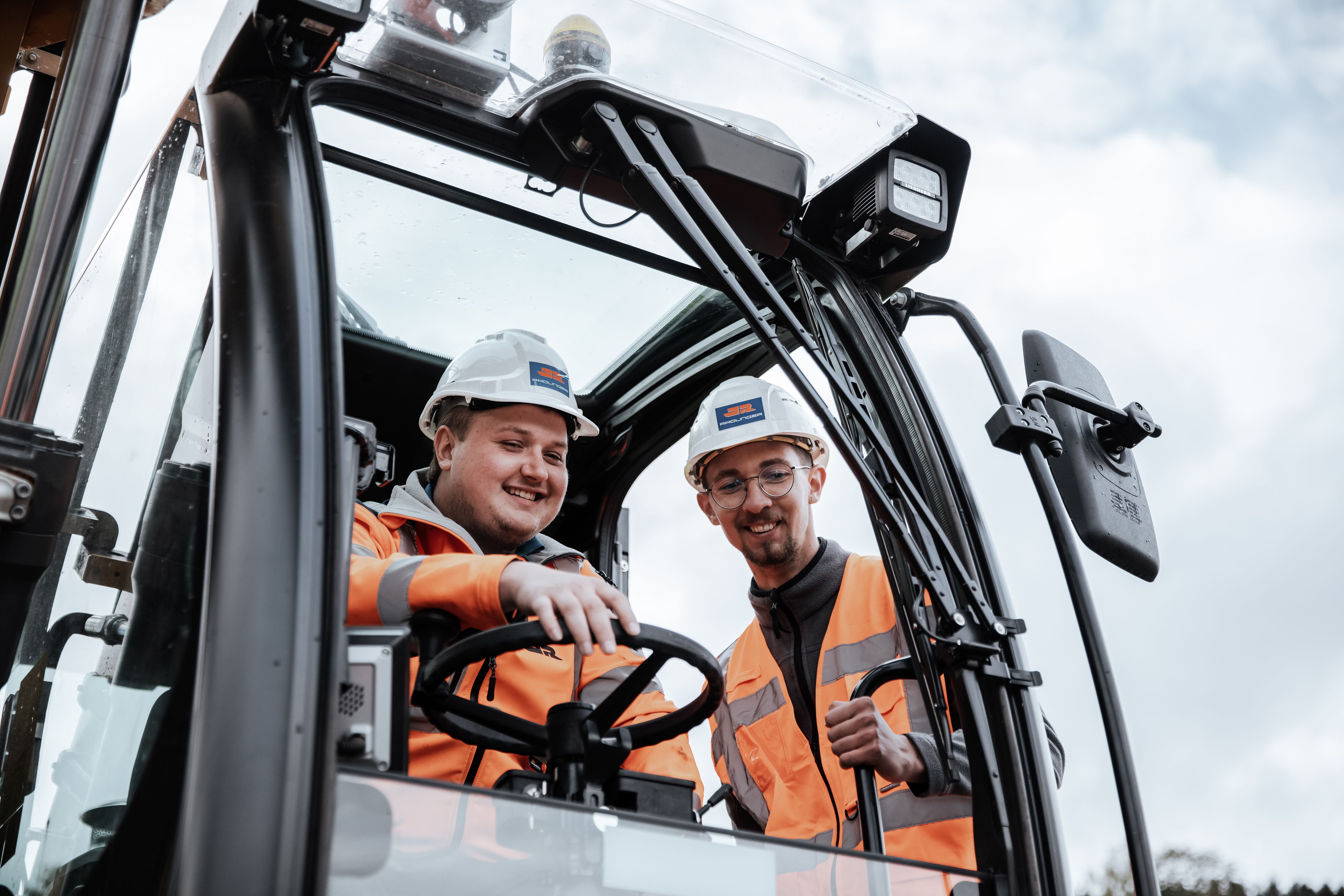 Zwei Rädlinger Bauarbeiter mit Bauhelmen in Baumaschine