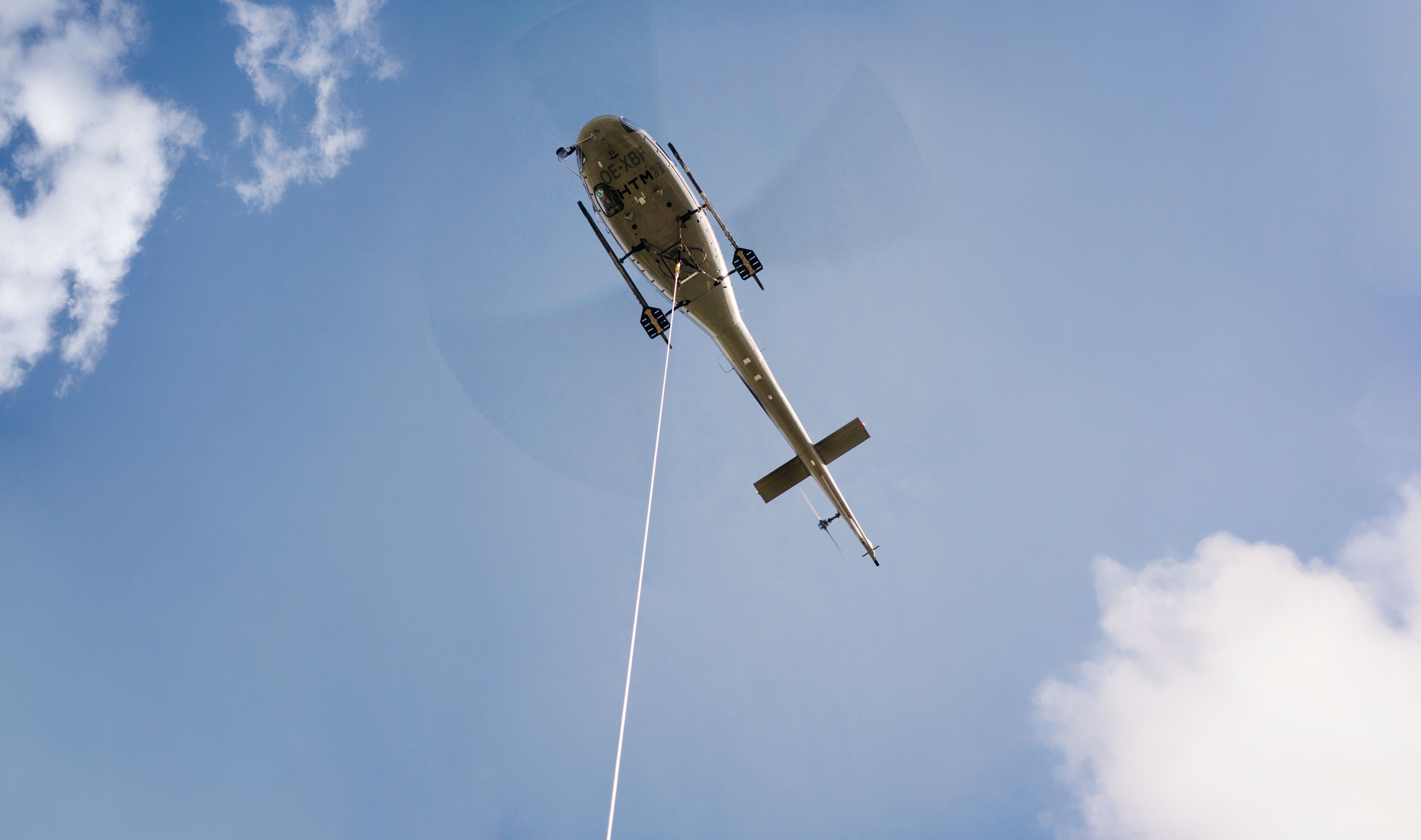 Der Helikopter fliegt über das Fußballfeld und transportiert dabei die Masten