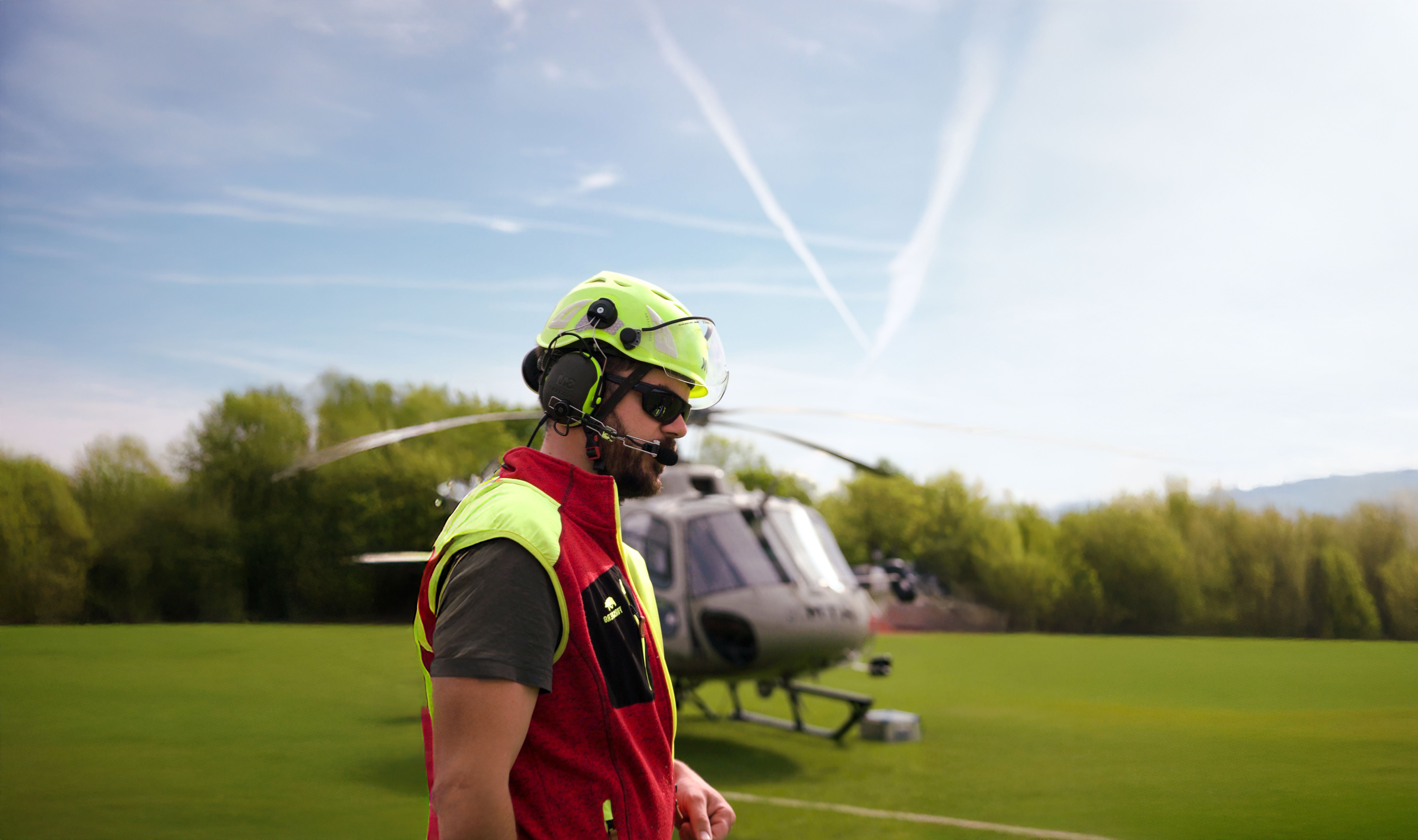 Der Pilot vor seinem Helikopter auf dem Sportplatz Poing
