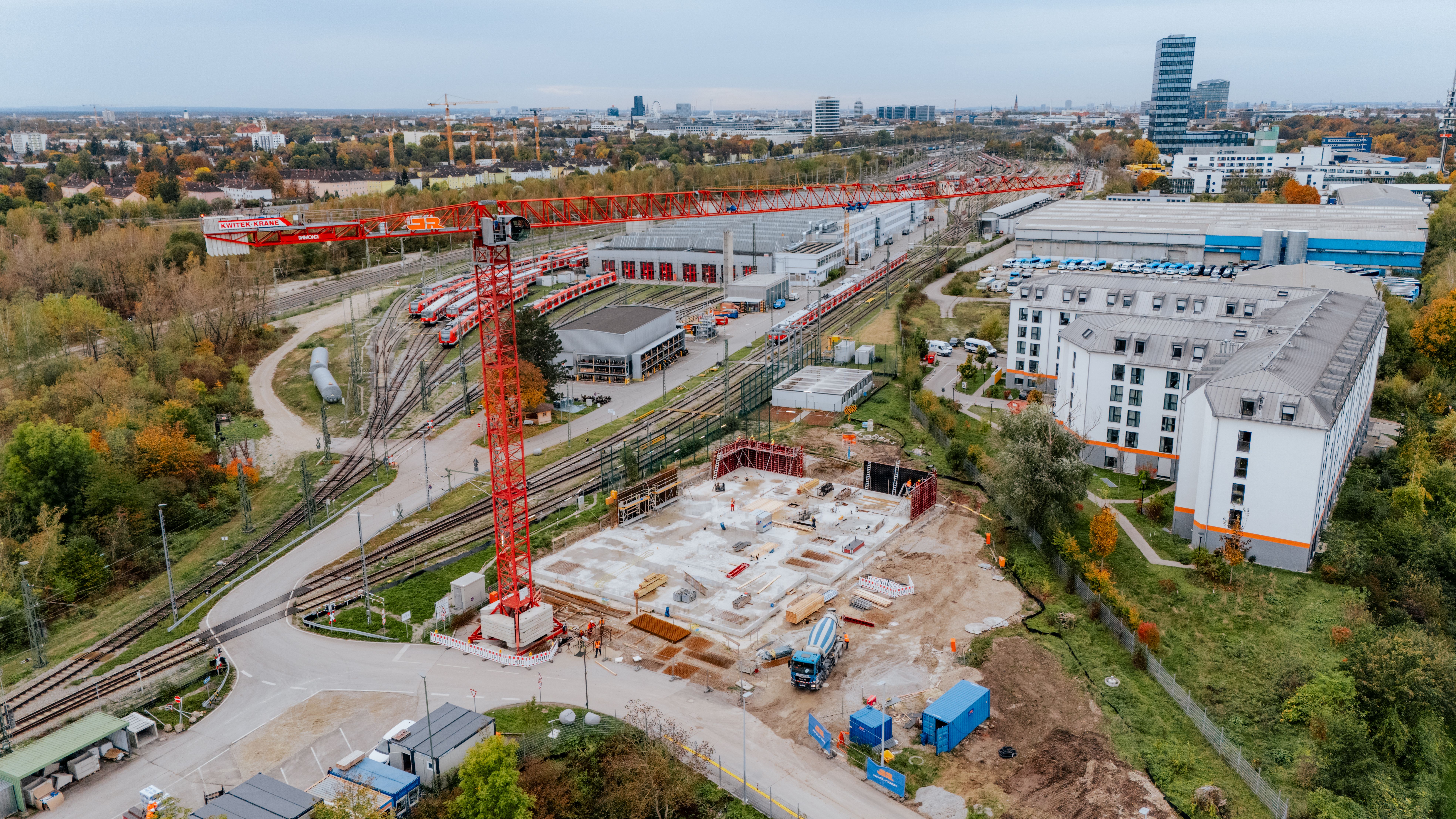 Die Baustelle von oben betrachtet. Zu sehen ist das Betonfundament, einige Baufahrzeuge sowie ein Baukran. Daneben befinden sich die Gleise und die DB Werkstatt