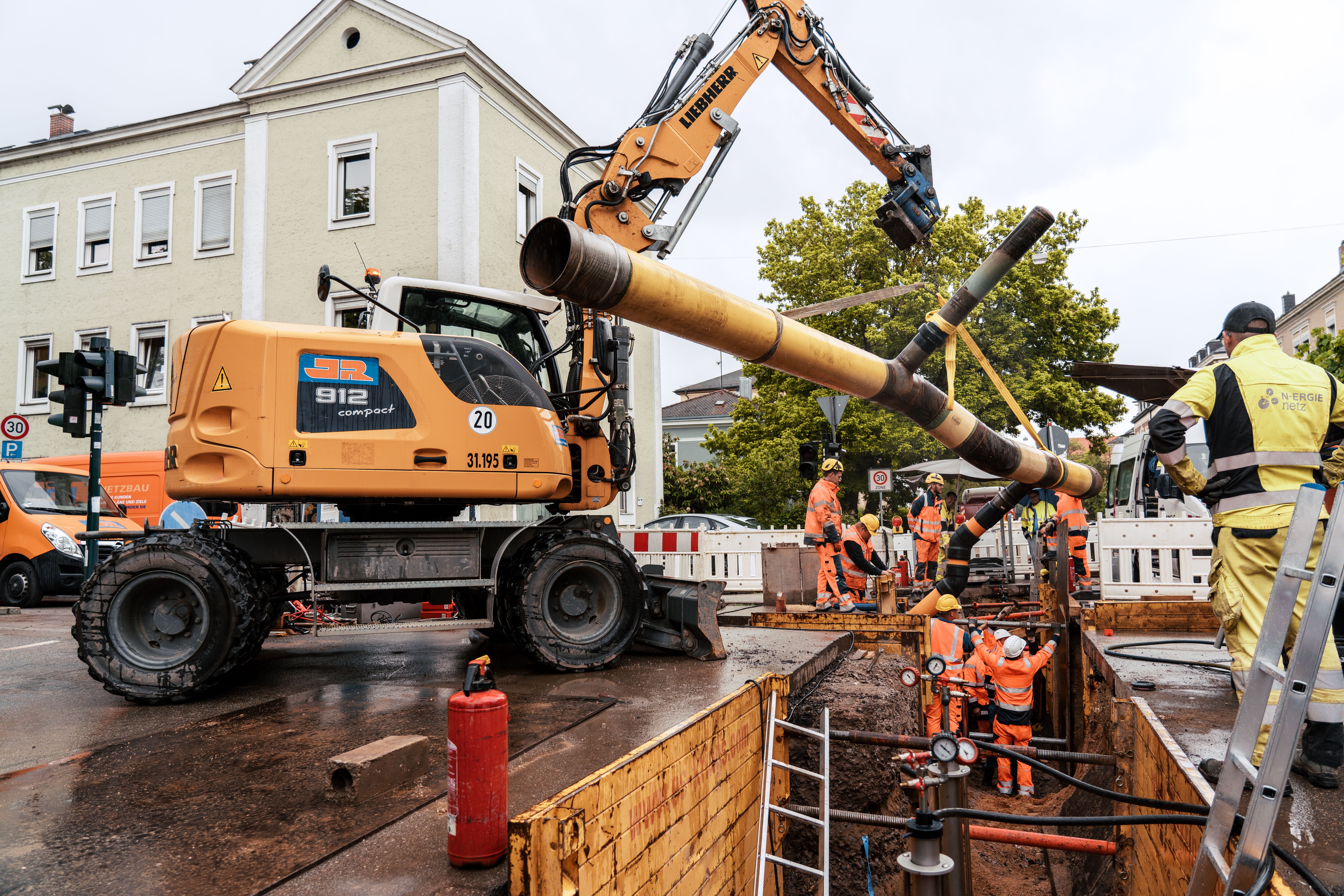 Ein Bagger hebt das neue Wasserleitungsrohr in die Baugrube ein