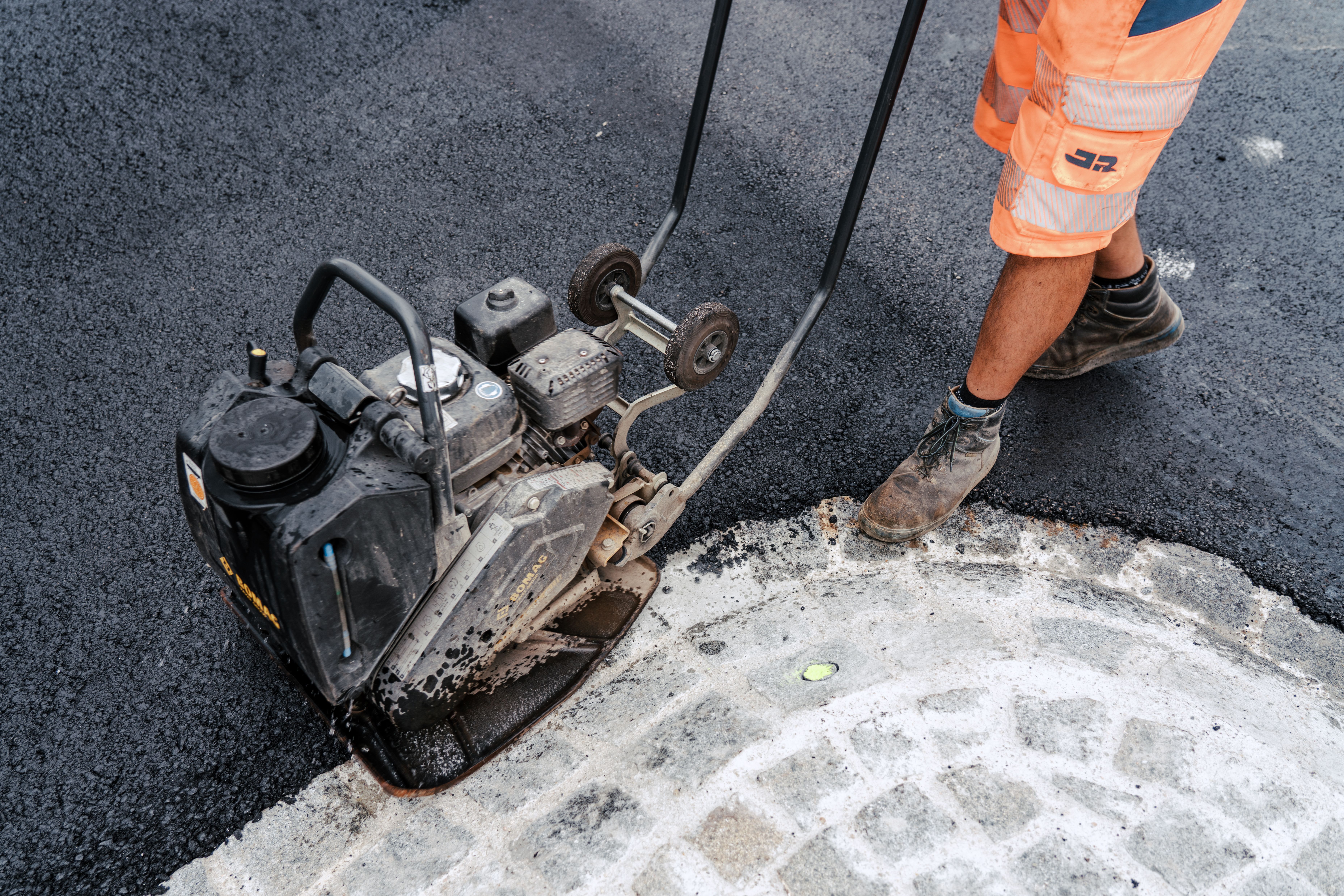 Mitarbeiter führt Arbeiten mit der Rüttelplatte durch