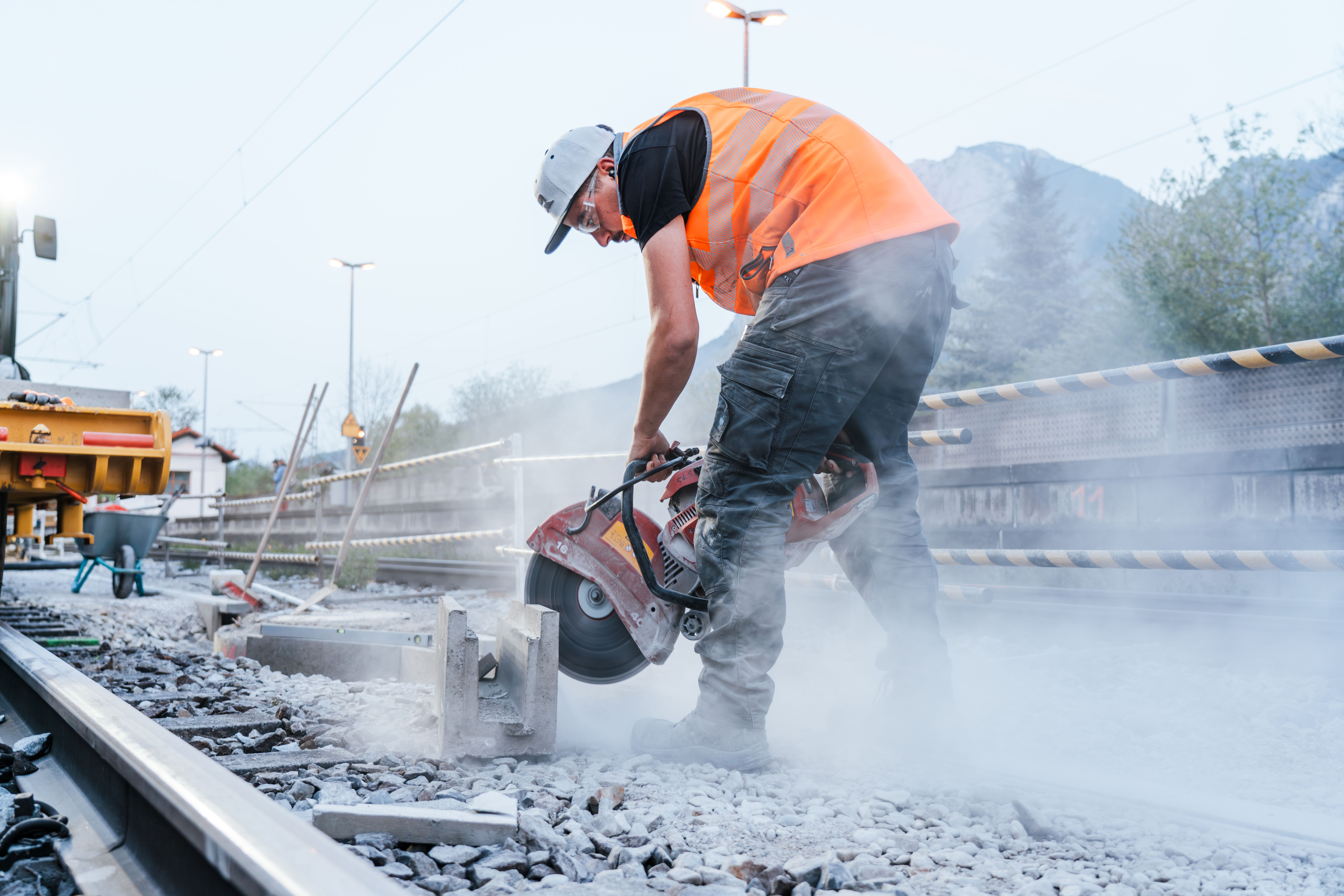 Mitarbeiter führt Flexarbeiten an einem Betonstück im Gleisbereich durch