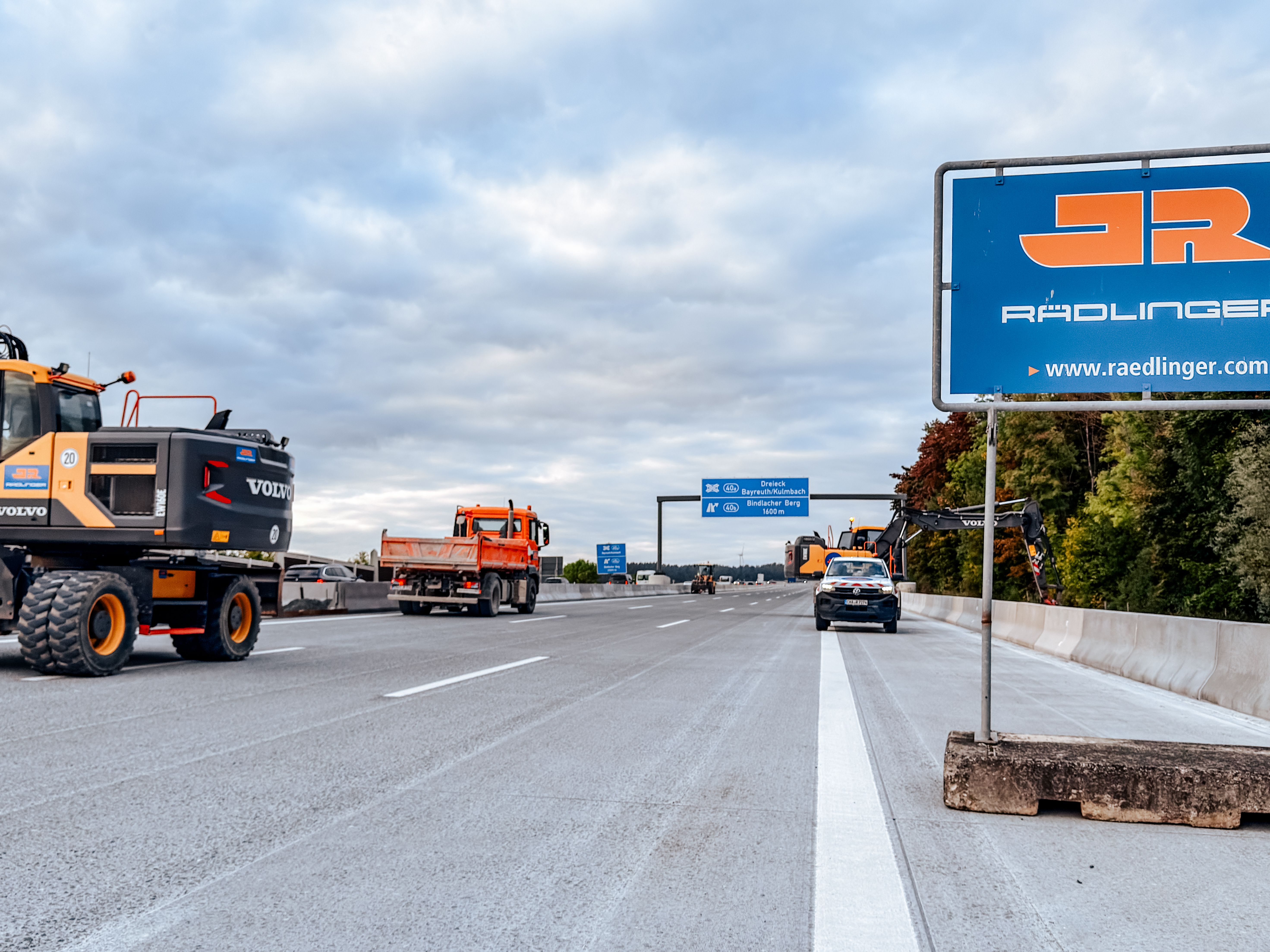 Baustellenfahrzeuge auf der frisch betonierten Fahrbahn der A9 mit JR Baustellenschild im Vordergrund