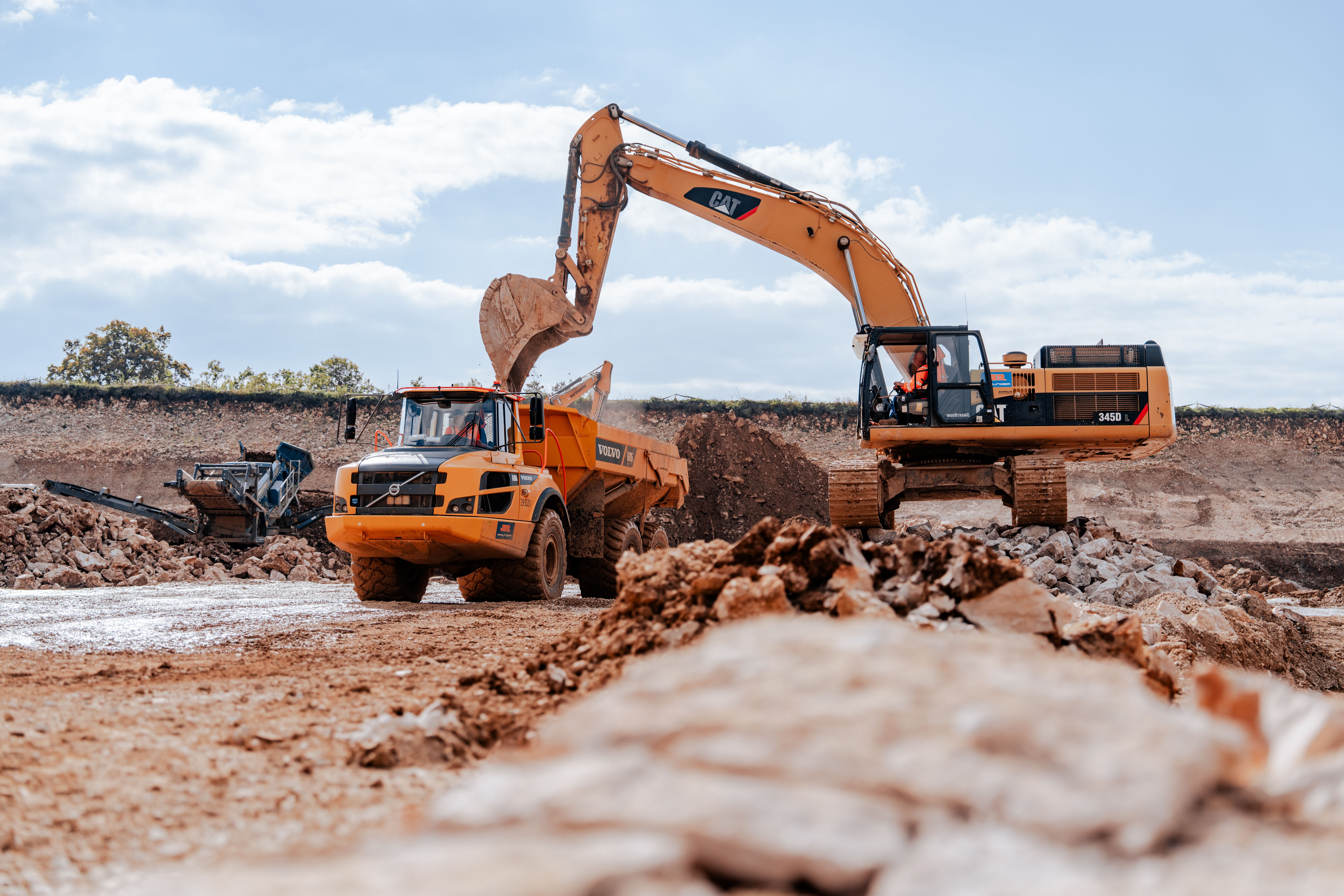Pumpspeicherkraftwerk Happurg, Sanierung Oberbecken: Bagger belädt Dumper mit abgebautem Gestein, im Hintergrund Recycling-Anlage