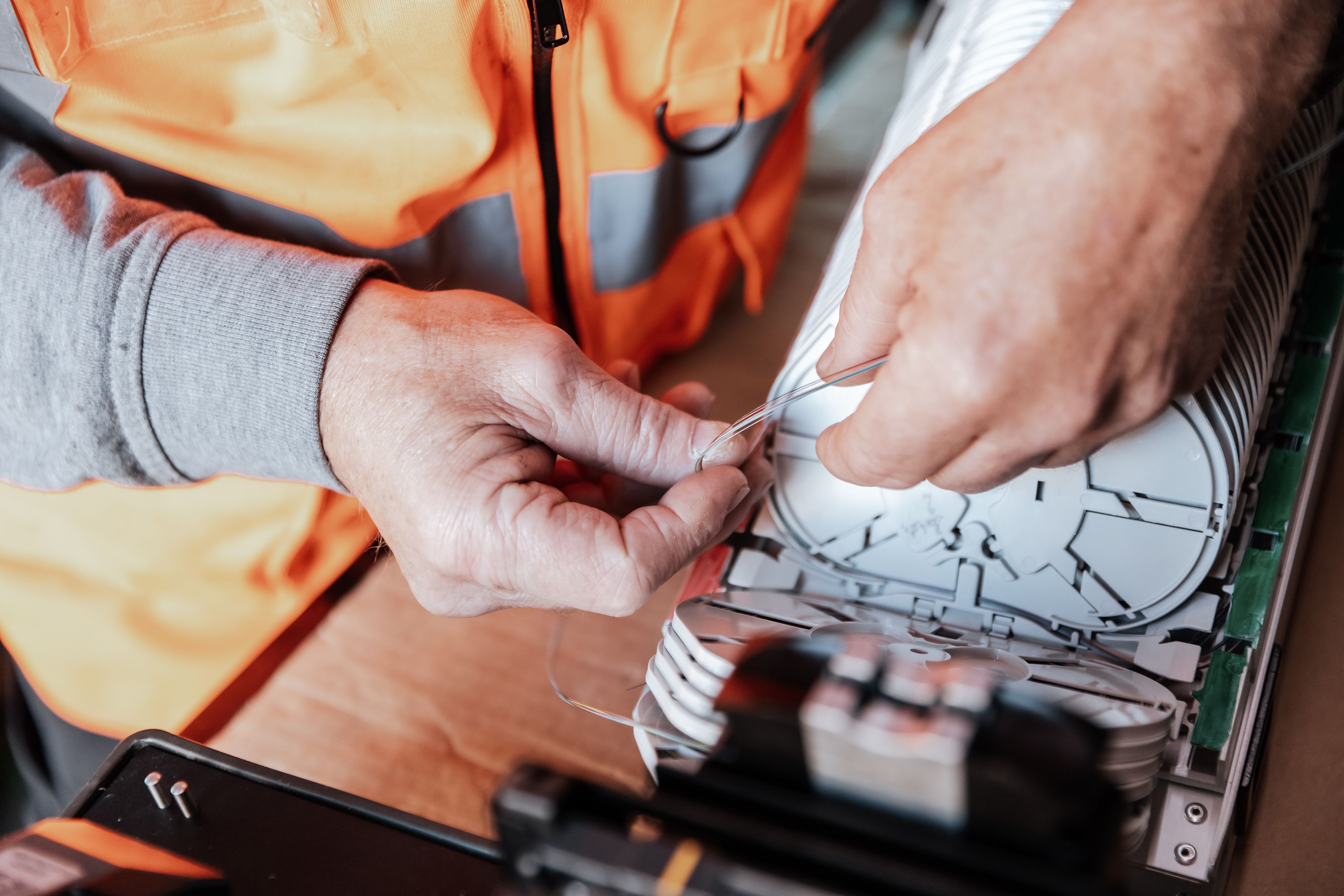 Mitarbeiter bestückt Spleißkassetten mit Glasfaserkabel (LWL-Technik)