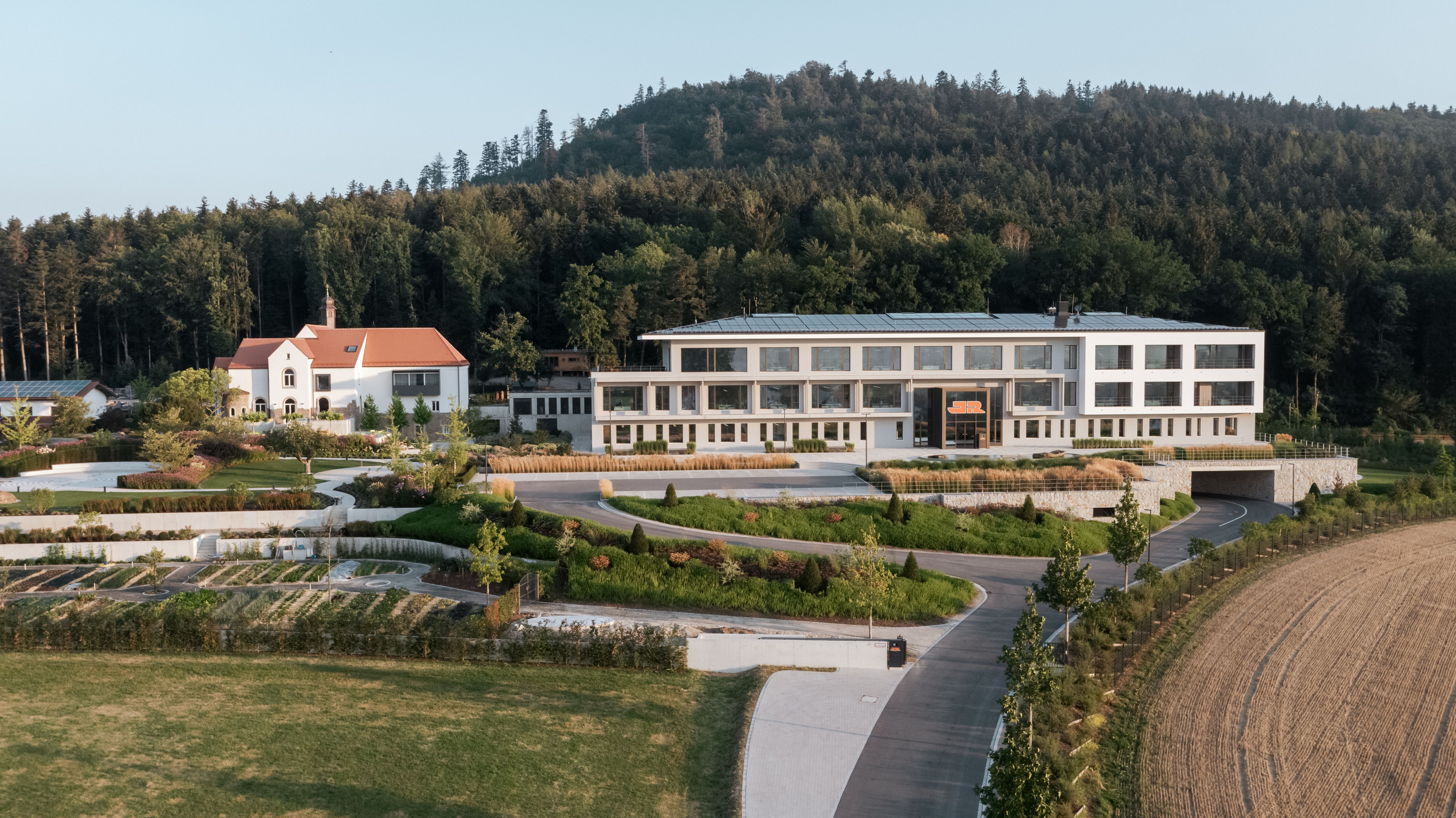 Hauptsitz der Josef Rädlinger Unternehmensgruppe in Cham, Gesamtansicht von außen mit Bürogebäude, Firmengarten und einem sanierten Kloster, das heute als Restaurant für die Mitarbeitenden genutzt wird