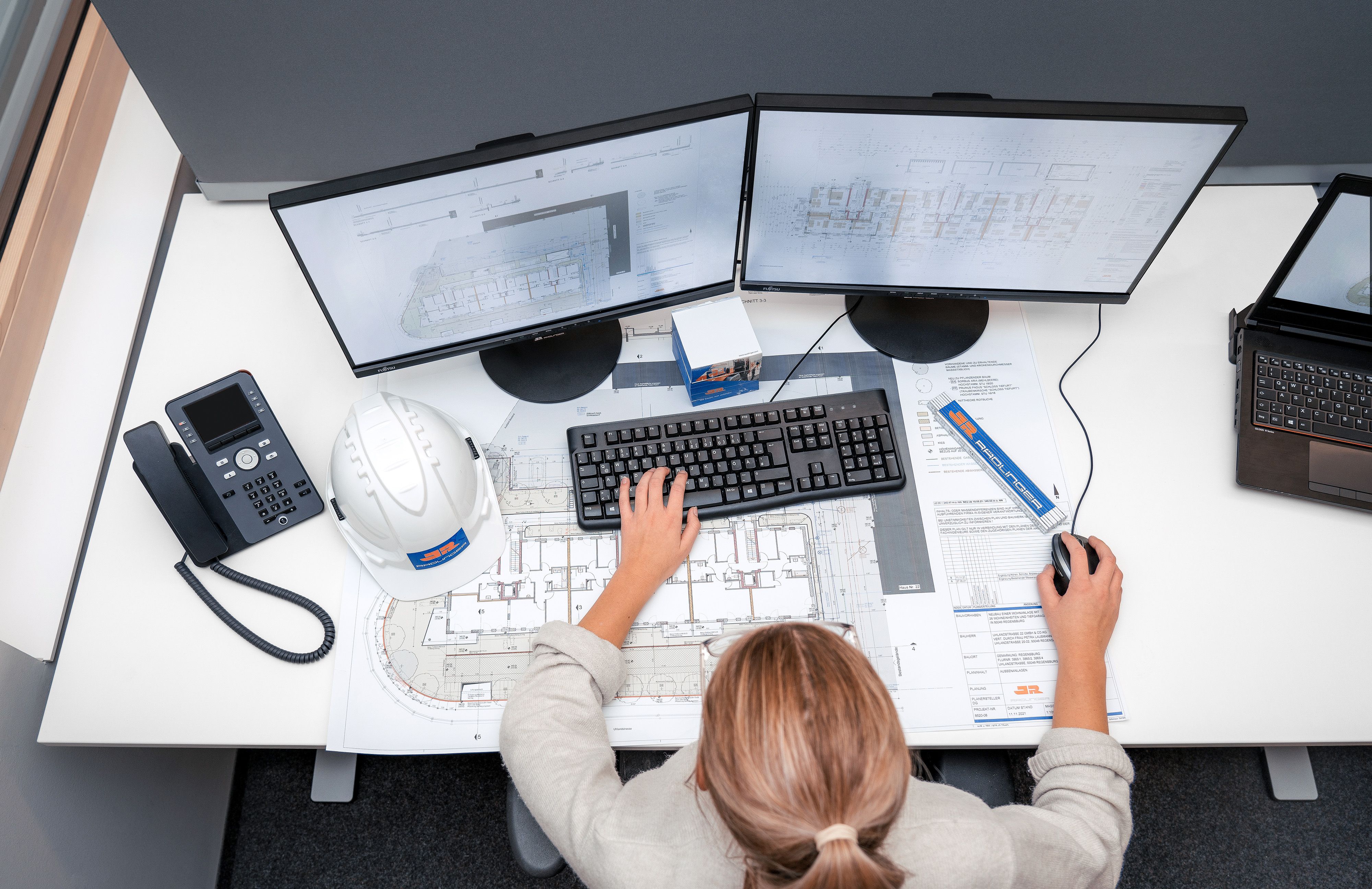 Eigene Abteilung für Architektur bei Rädlinger: Mitarbeiterin sieht sich Baupläne auf dem PC und auf einem Plan an